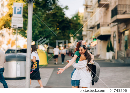 Happy meeting of two friends hugging in the street 94745296