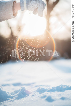 A woman holding snow in the backlight A woman holding snow in the backlight 94745495