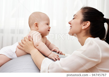 mother playing with her baby girl on a fitness ball mother playing with her baby girl on a fitness ball 94745767