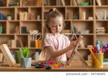Pretty little girl exercising with alphabet board, making words from colorful letters at preschool development class Pretty little girl exercising with alphabet board, making words from colorful letters at preschool development class 94746995