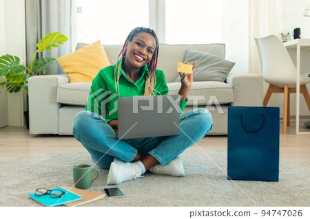 Online shopping and delivery. Excited african american lady showing credit card using laptop, advertising sales offer Online shopping and delivery. Excited african american lady showing credit card using laptop, advertising sales offer 94747026
