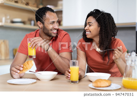 Laughing handsome millennial black wife and husband enjoy breakfast together in morning Laughing handsome millennial black wife and husband enjoy breakfast together in morning 94747031