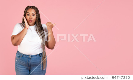 Amazed Black Woman Pointing Thumb Finger Aside On Pink Background 94747250