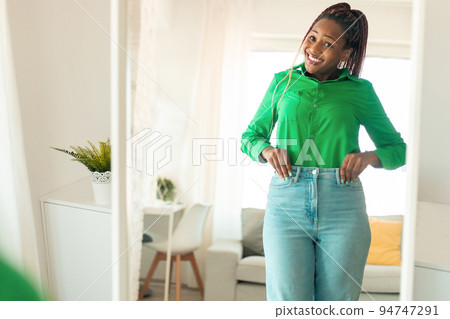 Female beauty and self-confidence. Positive black woman posing near mirror after slimming and successful weight loss Female beauty and self-confidence. Positive black woman posing near mirror after slimming and successful weight loss 94747291