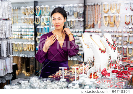 Young adult woman choosing jewelry in store 94748304