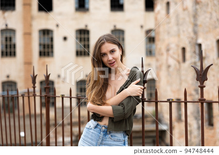 Woman in unbuttoned blouse posing near fence 94748444