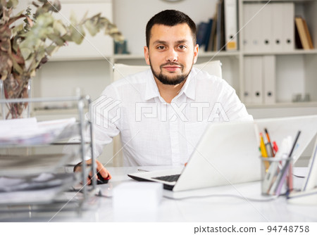 Positive man office worker using laptop during workday 94748758