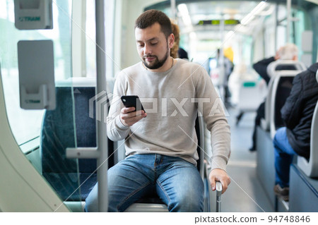 Portrait of european man standing in tram carriage and using phone 94748846
