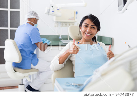 Portrait of satisfied woman visiting dentist giving thumbs up in dental clinic 94748877