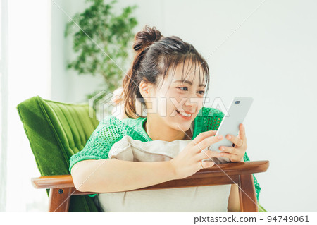 A woman lying on the sofa and looking at her smartphone A woman lying on the sofa and looking at her smartphone 94749061