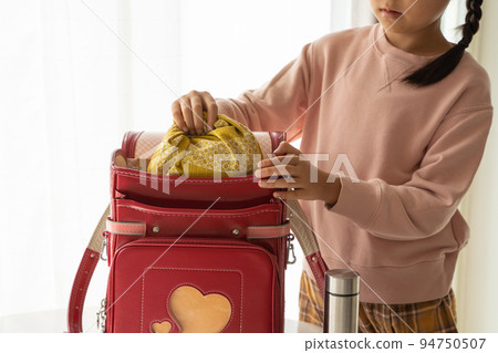 Elementary school student who puts a lunch in a school bag 94750507