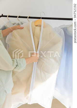 aesthetic laundry concept_covering clean clothes in plastic bags after dry cleaning 94752192