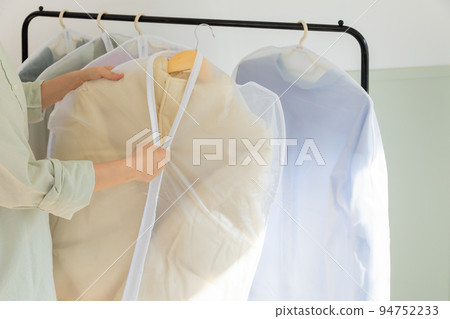 aesthetic laundry concept_covering clean clothes in plastic bags after dry cleaning 94752233