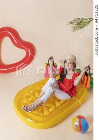 summer vacation trip with friends concept series_korean beautiful asian young woman holding shopping bags sitting on pool floats 94753829