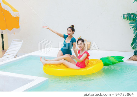 summer vacation trip with friends concept series_korean beautiful asian young women sitting on pool floats and playing on the water 94753864