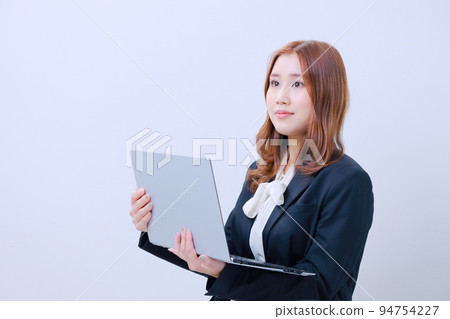 A young woman in a suit holding an open PC A young woman in a suit holding an open PC 94754227