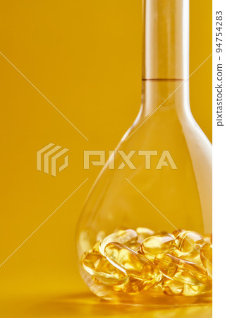 Omega-3 fatty acid capsules on a blue background in a flask. The concept of medicine and healthy living. Vertical photo. 94754283