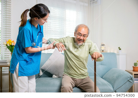 Young woman help support orthopedic patients to get up with walking cane at home 94754300