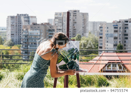 Young artist paints against the background of the city 94755574