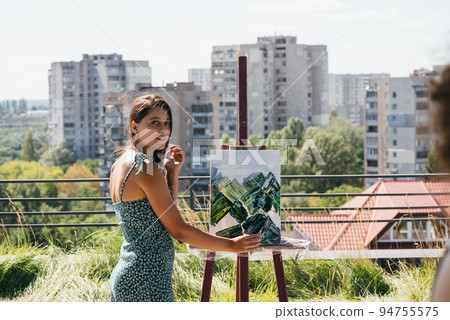 Young artist paints against the background of the city Young artist paints against the background of the city 94755575