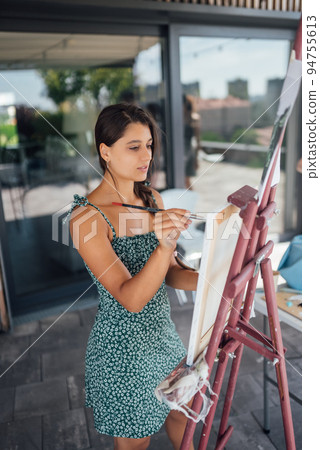 Woman drawing her picture on canvas with oil colors 94755613