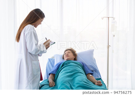 A young beautiful doctor is checking an old patient woman. 94756275