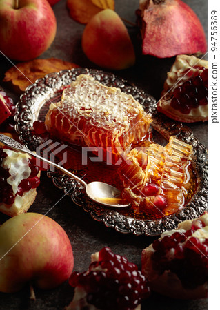 Honeycomb, apples, and pomegranate on an old stone table. 94756389