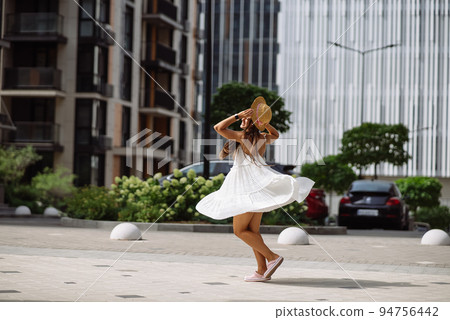 Beautiful pretty woman in white dress walking at city street Beautiful pretty woman in white dress walking at city street 94756442