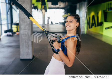 Woman doing exercises with trx fitness straps in the gym Woman doing exercises with trx fitness straps in the gym 94756458