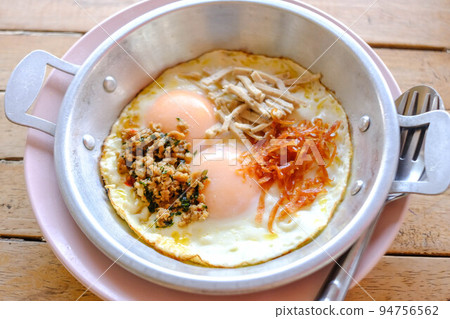 Pan-fried eggs with toppings on the wooden table. Pan-fried eggs with toppings on the wooden table. 94756562