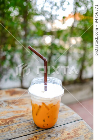 Iced Thai milk tea on a wooden table. Iced Thai milk tea on a wooden table. 94756571