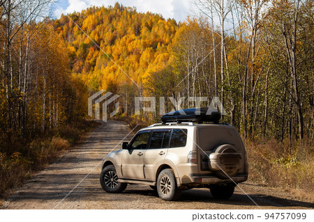 Dirty SUV on scenic autumn road in the forest 94757099