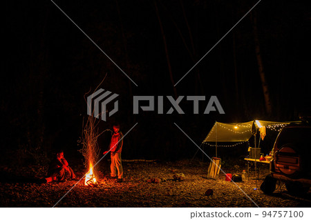 A couple at the campfire in autumn forest in the night. A couple at the campfire in autumn forest in the night. 94757100