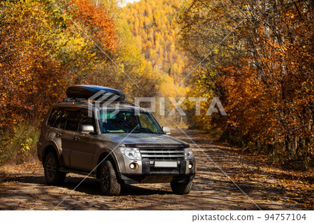 Mitsubishi Pajero on scenic autumn road in the forest 94757104
