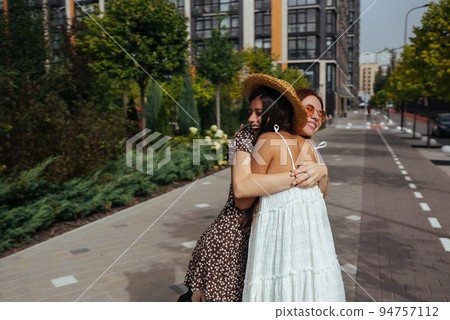 Happy meeting of two friends hugging in the street 94757112
