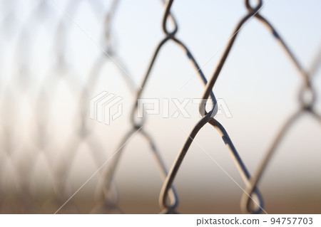 Closeup of chain link fence. Mesh netting on gray background 94757703