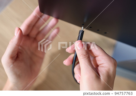 Person hand connects a black USB-C or Type C power cable to computer Person hand connects a black USB-C or Type C power cable to computer 94757763