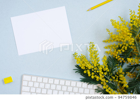 White sheet of paper for text copy space surrounded by spring mimosa, wireless keyboard with yellow pencil, watercolors in ditches on a blue background. Workplace of a blogger, artist, or calligrapher White sheet of paper for text copy space surrounded by spring mimosa, wireless keyboard with yellow pencil, watercolors in ditches on a blue background. Workplace of a blogger, artist, or calligrapher 94759846