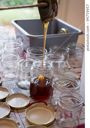 Filling of glass jars of honey on a table 94759957