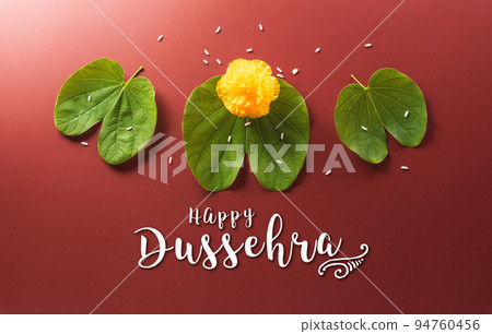 Happy Dussehra. Yellow flowers, green leaf and rice on dark paper background. Dussehra Indian Festival concept. Happy Dussehra. Yellow flowers, green leaf and rice on dark paper background. Dussehra Indian Festival concept. 94760456