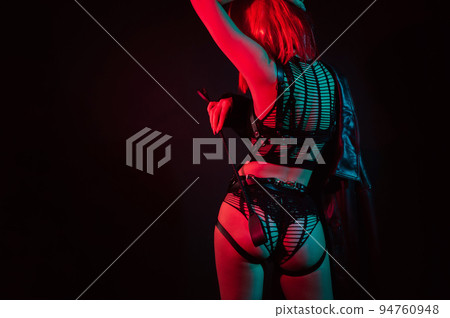 woman with a sexy ass with red hair in beautiful underwear holds leather whip flogger in her hand for BDSM sex 94760948