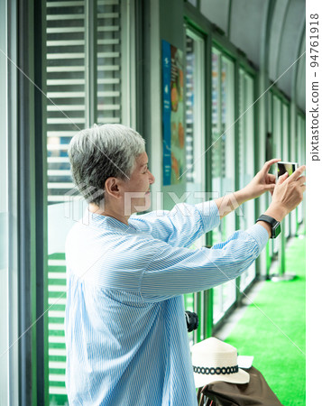 A 60-year-old mature Asian woman writes wisdom-type self-beating, travel or sightseeing exploration concept. 94761918