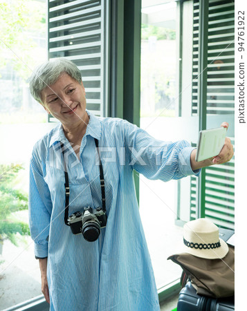 一位 60 歲的成熟亞洲女性寫下智慧型的自我打擊、旅行或觀光探索概念。 一位 60 歲的成熟亞洲女性寫下智慧型的自我打擊、旅行或觀光探索概念。 94761922