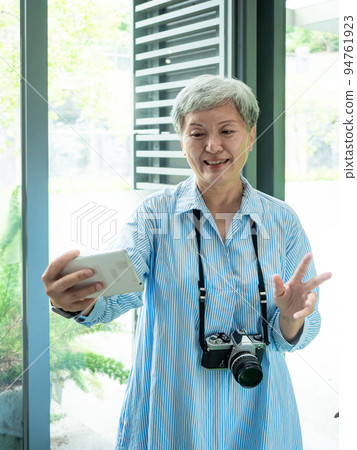 A 60-year-old mature Asian woman writes wisdom-type self-beating, travel or sightseeing exploration concept. 94761923