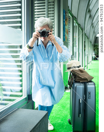 60 多歲的亞洲女性揮舞著單眼觀察機或底部單相機,旅行或觀光探索概念。 60 多歲的亞洲女性揮舞著單眼觀察機或底部單相機,旅行或觀光探索概念。 94761933