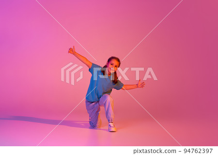 Portrait of caucasian little girl, kid in casual bright clothes dancing isolated over pink background in neon. Action, dance, happy childhood Portrait of caucasian little girl, kid in casual bright clothes dancing isolated over pink background in neon. Action, dance, happy childhood 94762397