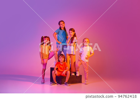 Dance group of happy, active little girls and boys in bright clothes in action isolated on pink background in neon. Concept of music, fashion, art, childhood 94762418