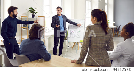 Business coach meets with team of people and gives presentation with office whiteboard 94762528