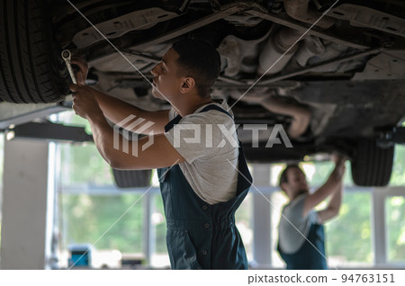 Car mechanics fixing the client vehicle together 94763151