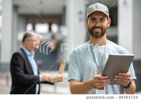 Bearded elegant businessman taking the box from a courrier 94763159